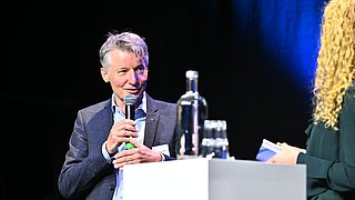 Eine Person hält einen Vortrag auf einer Bühne.