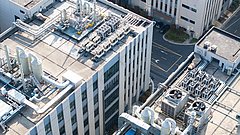 Dachansicht mehrerer Industriegebäude mit großen Lüftungsanlagen, Rohrleitungen und Klimageräten.