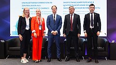 Fünf Personen stehen nebeneinander auf einer Bühne vor einer Leinwand mit dem Titel „Energietransformation in Zentralasien als wirtschaftliche Chance“. Von links nach rechts: Kim Lakeit (Leiterin Stabsstelle Internationale Kooperationen der dena), Ekaterina Galitsyna (Leiterin der Abteilung für Osteuropa, Zentralasien und den Südkaukasus, KfW IPEX-Bank), Dr. Urs Engels (Leiter des Referats für Zentralasien, BMWK), Sungat Yessimkhanov (Vizeminister für Energie der Republik Kasachstan) und Maxim Zubov (Generaldirektor Siemens Energy Kasachstan, Vizepräsident für die Subregionen Türkei, Südkaukasus und Zentralasien). Alle tragen formelle Businesskleidung und stehen lächelnd vor einer Konferenzbühne mit Sesseln und Mikrofonen