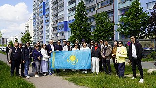Gruppe von Menschen mit der Flagge von Kasachstan vor einem Mehrfamilienhaus