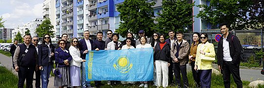 Gruppe von Menschen mit der Flagge von Kasachstan vor einem Mehrfamilienhaus