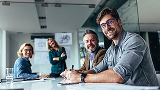 Man sieht einen Gruppe von Geschäftsmenschen (2 Männer und 2 Frauen) während einer Präsentation.
