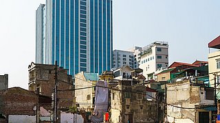 Ruinenhäuser auf Hochbau-Hintergrund Kontrast auf der Minh-Khai-Straße, Hanoi, Vietnam