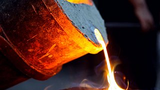 Glühendes Metall wird aus einem Schmelztiegel in einer Gießerei gegossen, Leitfaden zur Steigerung der Energieeffizienz und Senkung von CO2-Emissionen in der Gießerei-Industrie