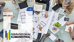 Ein Tisch mit mehreren Personen, die an Plänen und Skizzen arbeiten. Sichtbare Materialien sind Notizblätter, ein Laptop und ein Pflanzenarrangement. Links unten das Logo 'GEBÄUDEFORUM KLIMANEUTRAL'.