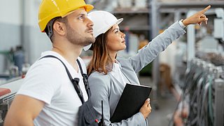 Ein Fabrikarbeiter und eine Ingenieurin bei einer Inspektion. 