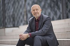 Porträt von Andreas Kuhlmann, der auf einer Treppe sitzt