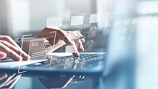 Eine Person tippt an einem Laptop, das Bild ist mit einer stilisierten Vernetzung aus Ordnern und Verknüpfungen überzogen