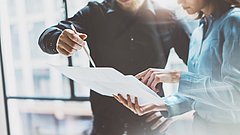 Zwei Personen unterhalten sich und sehen dabei ein Schriftstück an