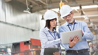 Engineers with laptop in factory
