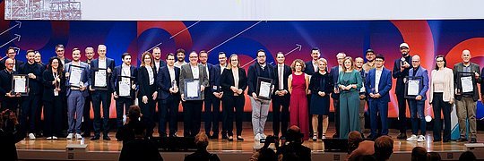 Auf der Bühne sind die Preisträger, die Laudatoren sowie die Moderatorin der Preisverleihung des Energy Efficiency Awards 2025 zu sehen.