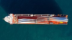 Luftaufnahme eines Schwerlasttransportschiffs beladen mit elektrischen Turbinenschaufeln.
