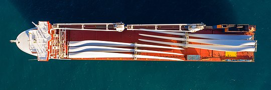 Luftaufnahme eines Schwerlasttransportschiffs beladen mit elektrischen Turbinenschaufeln.