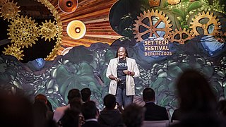 Eine Moderatorin steht auf der Bühne beim SET Tech Festival 2025