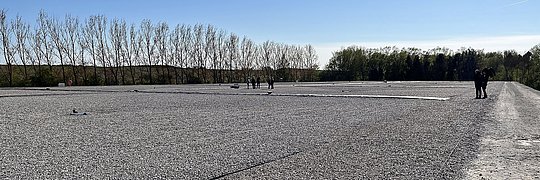 Kiesfeld mit mehreren Personen, die darauf spazieren gehen, umgeben von einer natürlichen Umgebung.
