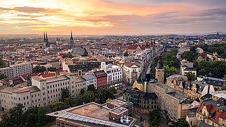 Stadtpanorama von Halle (Saale) bei Sonnenuntergang mit historischen Gebäuden, Kirchtürmen und dicht bebauten Straßen.