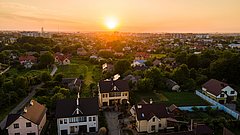 Fassade eines orangefarbenen Mehrfamilienhauses mit Balkonen und Fenstern, umgeben von kahlen Bäumen.