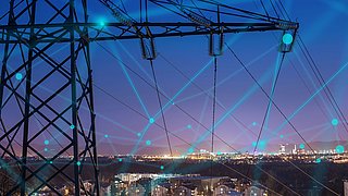 Strommast vor nächtlicher Stadt mit vernetzter digitaler Darstellung