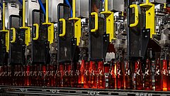 Frisch geformte Glasflaschen verlassen die Glasformanlage.