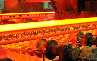 Blick durch ein rundes Fenster in einen Ofen mit intensivem Feuer und Flammen im Inneren.