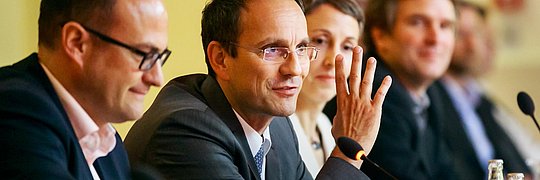 Mehrere Personen sitzen an einem Tisch, in der Mitte spricht Christian Stolte, Bereichsleiter Klimaneutrale Gebäude Prokurist, gestikulierend ins Mikrofon.