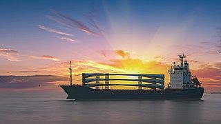 Ein Schiff mit Windradflügeln bei Sonnenuntergang.