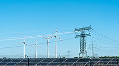Solarkollektoren, Windräder und Überlandleitungen befinden sich vor blauem Himmel