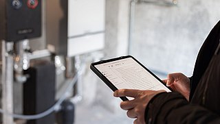 Person mit Tablet vor einer Heizung