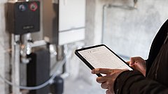 Person mit Tablet vor einer Heizung