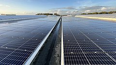 Eine großflächige Photovoltaik-Anlage auf einem Hallendach.