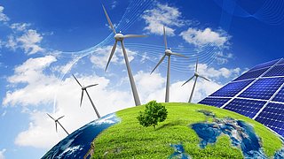 Erdöberfläche mit Windrad und Solarpanelen, darüber blauer Himmel mit Wolken