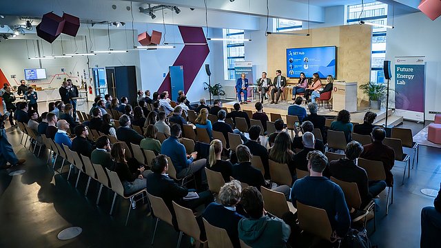 Gäste sitzen in Reihenbestuhlung vor der Bühne im Future Energy Lab