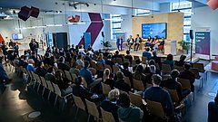 Gäste sitzen in Reihenbestuhlung vor der Bühne im Future Energy Lab