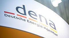 Logo der Deutschen Energie-Agentur (dena) mit orangefarbenem und gelbem Streifen unter dem Schriftzug, auf einem Banner.