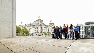 Gruppe von Menschen vor dem Reichstagsgebäude in Berlin mit sichtbaren deutschen Flaggen