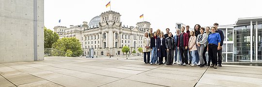 Gruppe von Menschen vor dem Reichstagsgebäude in Berlin mit sichtbaren deutschen Flaggen
