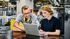 Ingenieure die in einer Werkhalle an einem Laptop arbeiten