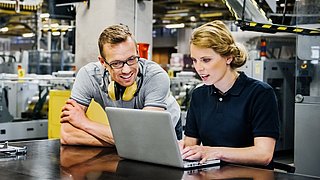 Ingenieure die in einer Werkhalle an einem Laptop arbeiten