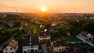 Fassade eines orangefarbenen Mehrfamilienhauses mit Balkonen und Fenstern, umgeben von kahlen Bäumen.