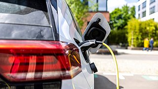 Ein weißes Elektroauto wird mit einem Ladekabel aufgeladen.