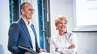 Christian Stolte (dena) und Corinna Enders (dena) stehen auf dem Podium