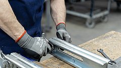 Ein Mitarbeiter arbeitet an einem metallenen Werkteil.