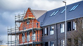 Ein Mehrfamiliengebäude von einem Baugerüst umhüllt