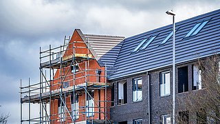 Ein Mehrfamiliengebäude von einem Baugerüst umhüllt