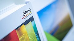 Das Bild zeigt mehrere Broschüren, darunter eine mit dem Logo 'dena' und dem Text 'German Energy Agency'. Die Broschüre hat eine bunte Gestaltung mit Farben in Rot, Gelb, Grün und Blau.