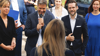 Robert Habeck spricht mit Mikrofon vor einer Gruppe von Menschen bei einem Besuch