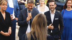 Robert Habeck spricht mit Mikrofon vor einer Gruppe von Menschen bei einem Besuch