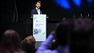 Eine Person hält einen Vortrag auf einer Bühne.