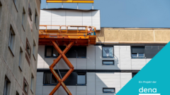 Fassade eines mehrstöckigen Gebäudes mit Hebebühne und zwei Arbeitern vor blauem Himmel und der Schriftzug "Ein Projekt der dena"