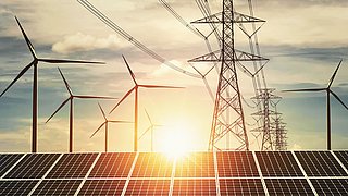 Solarpanel, Windräder und  Hochspannungsleitungen vor Sonnenuntergang 